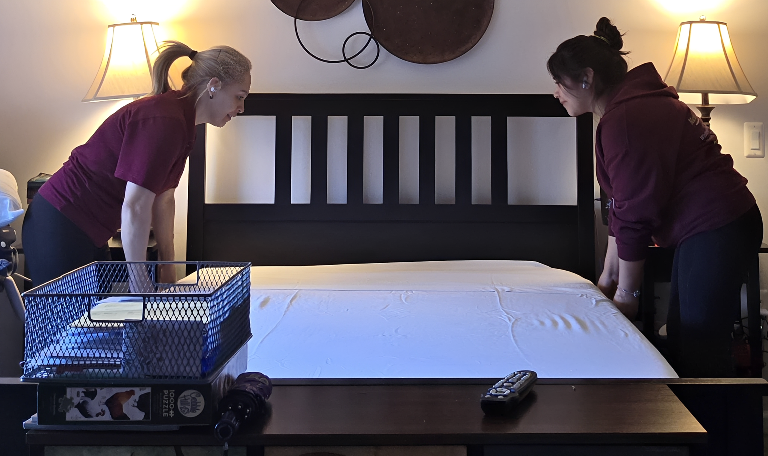 Two people making a bed together.
