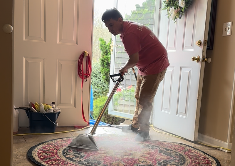 Person cleaning a colorful rug with a carpet cleaner.