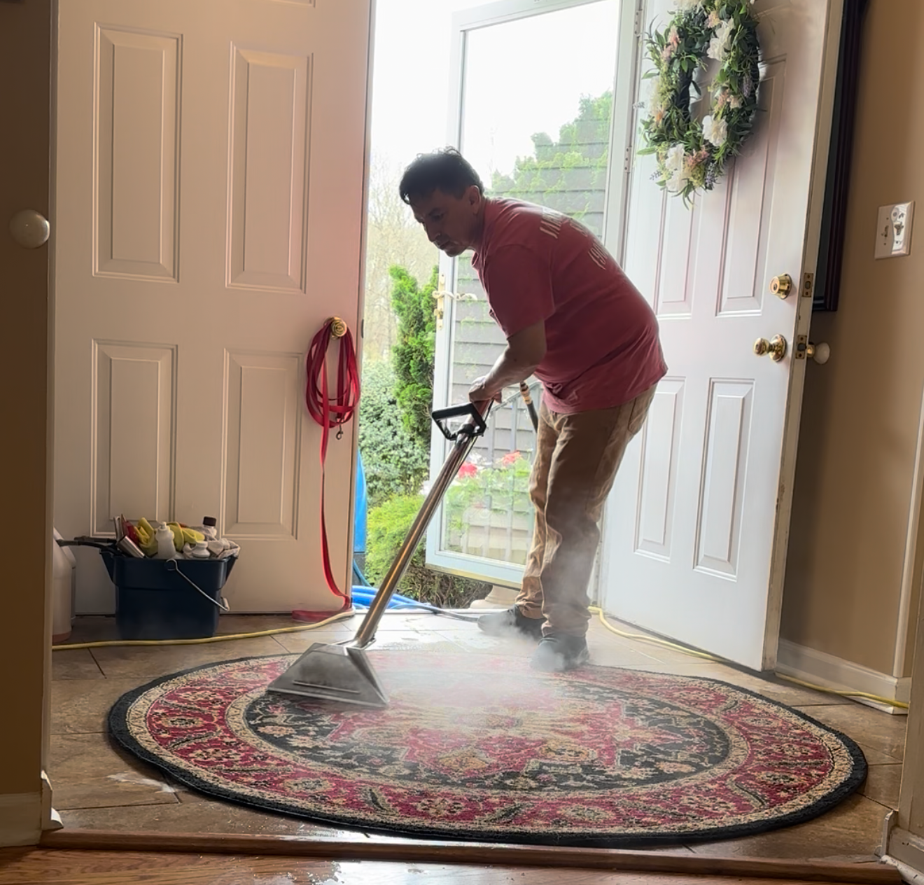 A person cleaning a circular rug with a vacuum cleaner near the entrance door.